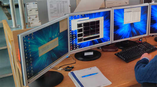 Büroarbeitsplatz mit mehreren Monitoren und Software für komplexe GNSS-Postprocessing-Auswertung.